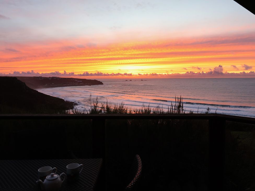 A sunset view over the ocean with a teapot and cups at Cragford in Sennen Cove