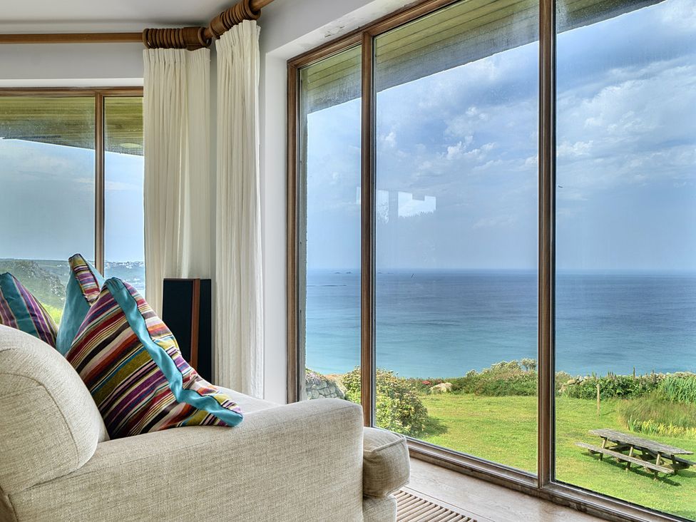 A living room with a sofa and large windows at Cragford in Sennen Cove