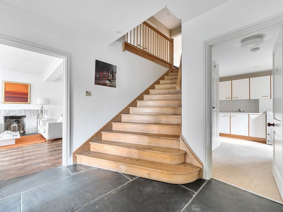 A hallway with a staircase and kitchen view at Cragford in Sennen Cove