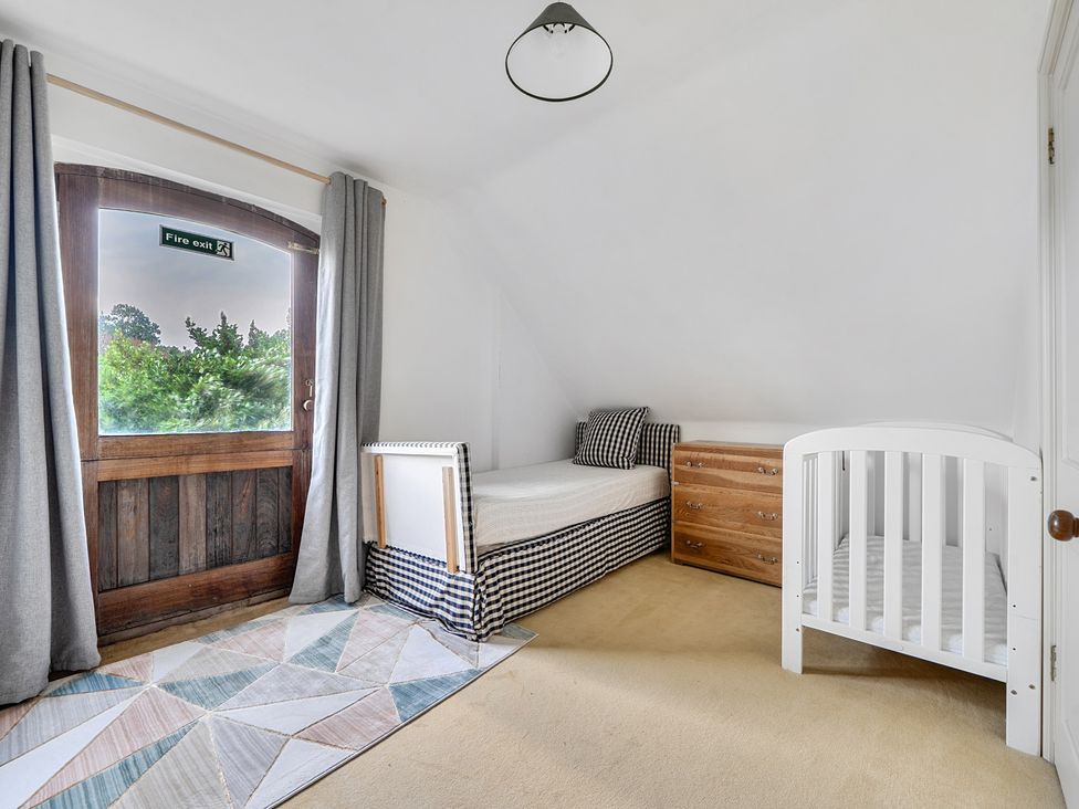 A bedroom with a bed, crib and chest of drawers at Cragford in Sennen Cove