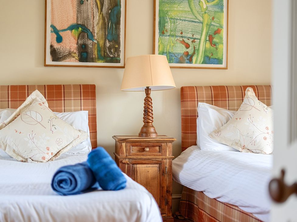 A bedroom with two beds, a lamp, and artwork at Cragford in Sennen Cove