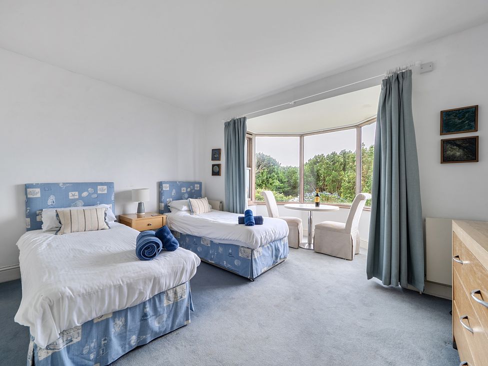 A bedroom with two beds and table at Cragford in Sennen Cove