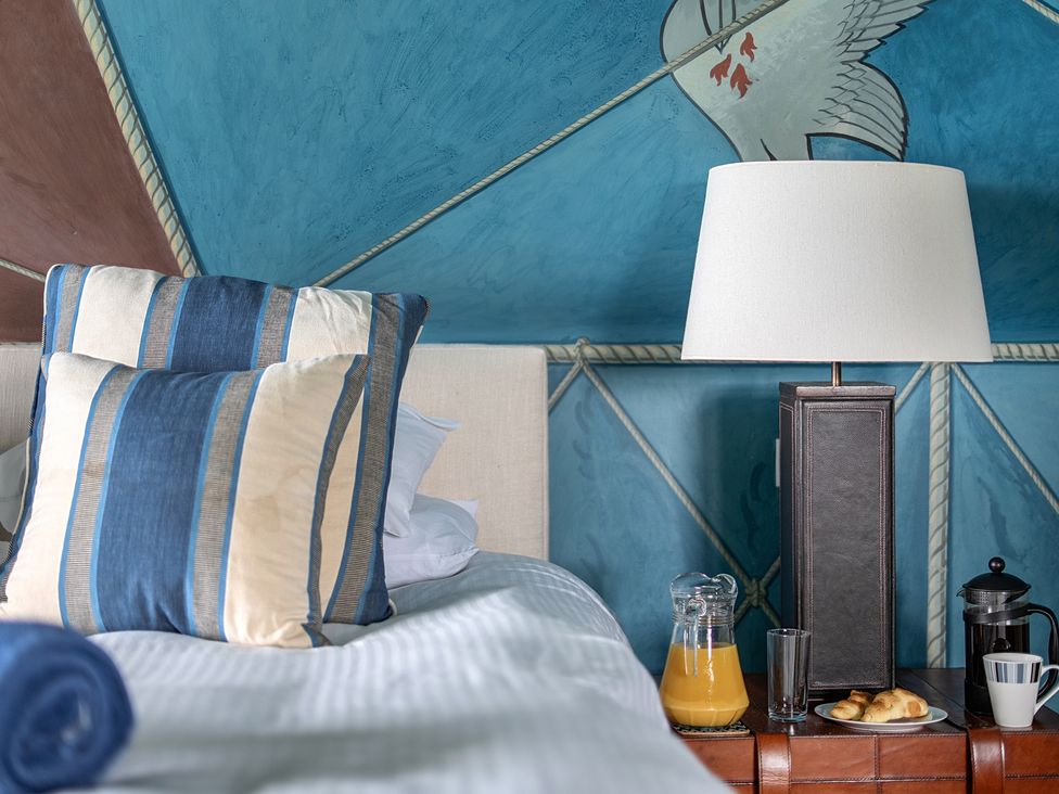 A bedroom with a bed, lamp, and breakfast items at Cragford in Sennen Cove