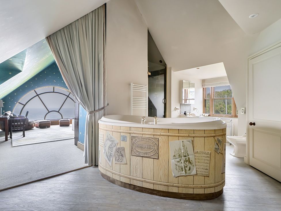 A bathroom with a bathtub and window at Cragford in Sennen Cove