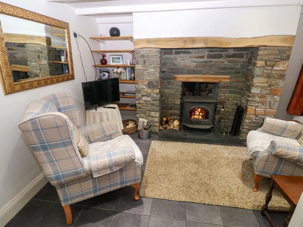 A living room with a fireplace and armchairs at Milk Wood Cottage in Laugharne