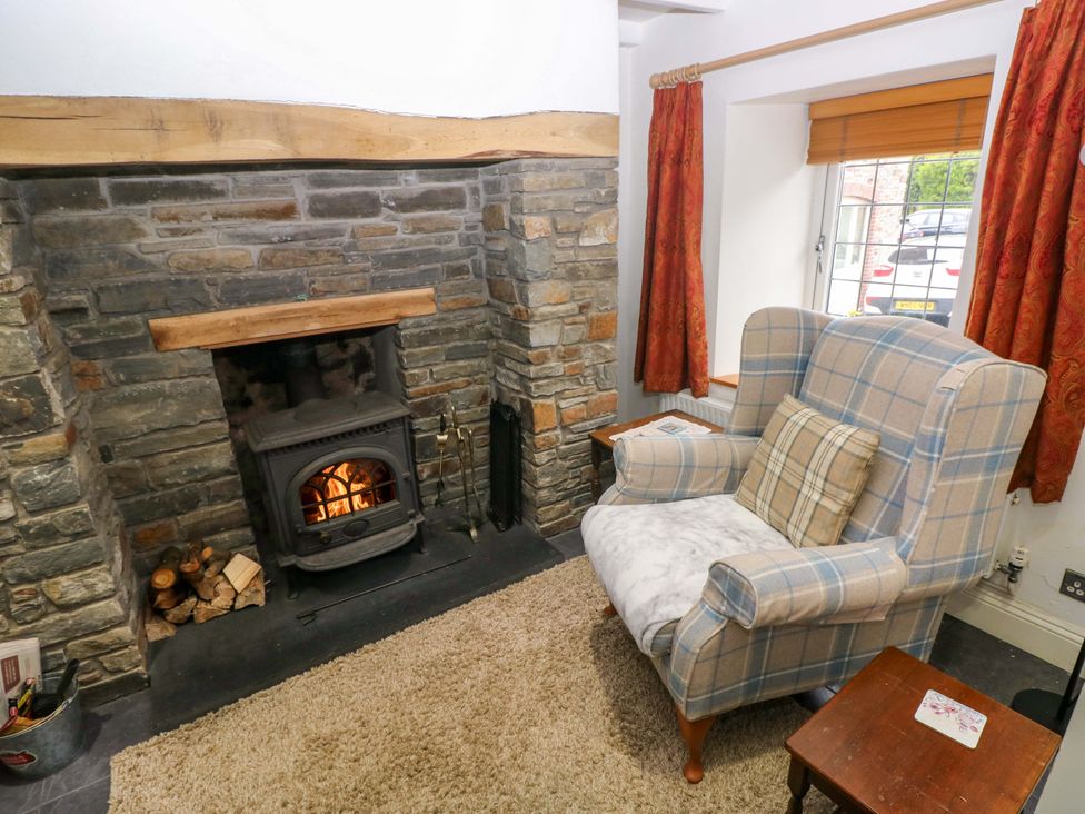 A living room with a fireplace and armchair at Milk Wood Cottage in Laugharne