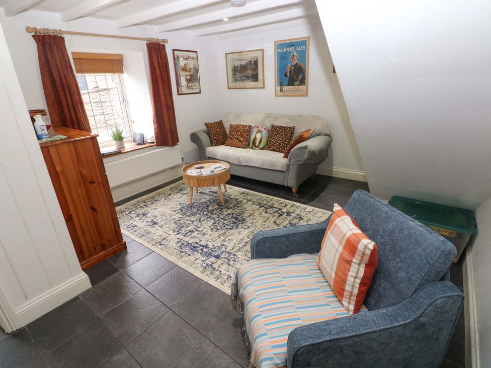 A living room with a sofa and armchair at Milk Wood Cottage Laugharne