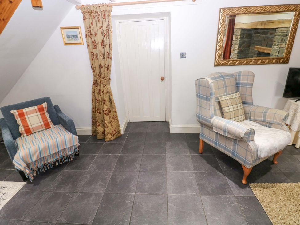 A living room with an armchair and sofa at Milk Wood Cottage in Laugharne