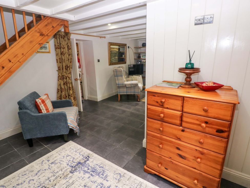 A living room with a chest of drawers and a chair at Milk Wood Cottage in Laugharne