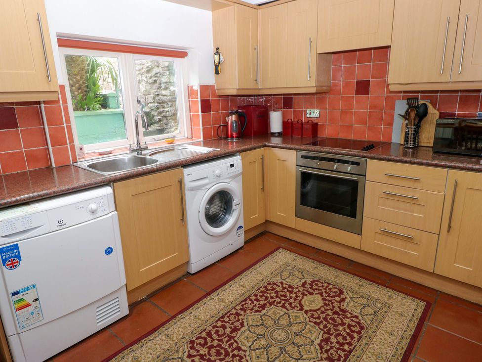 A kitchen with appliances and a window at Milk Wood Cottage in Laugharne