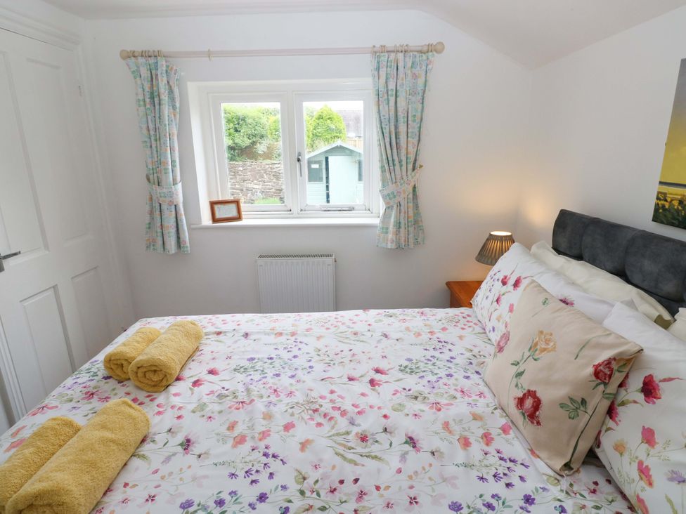 A bedroom with a bed and a window at Milk Wood Cottage in Laugharne