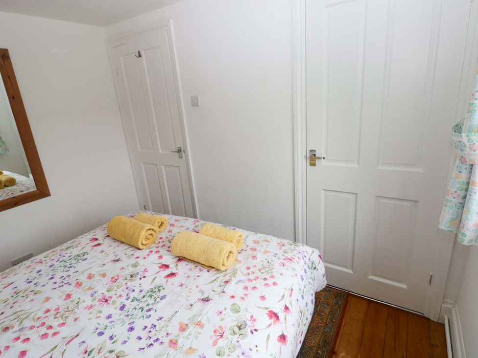 A bedroom with a bed and towels at Milk Wood Cottage in Laugharne