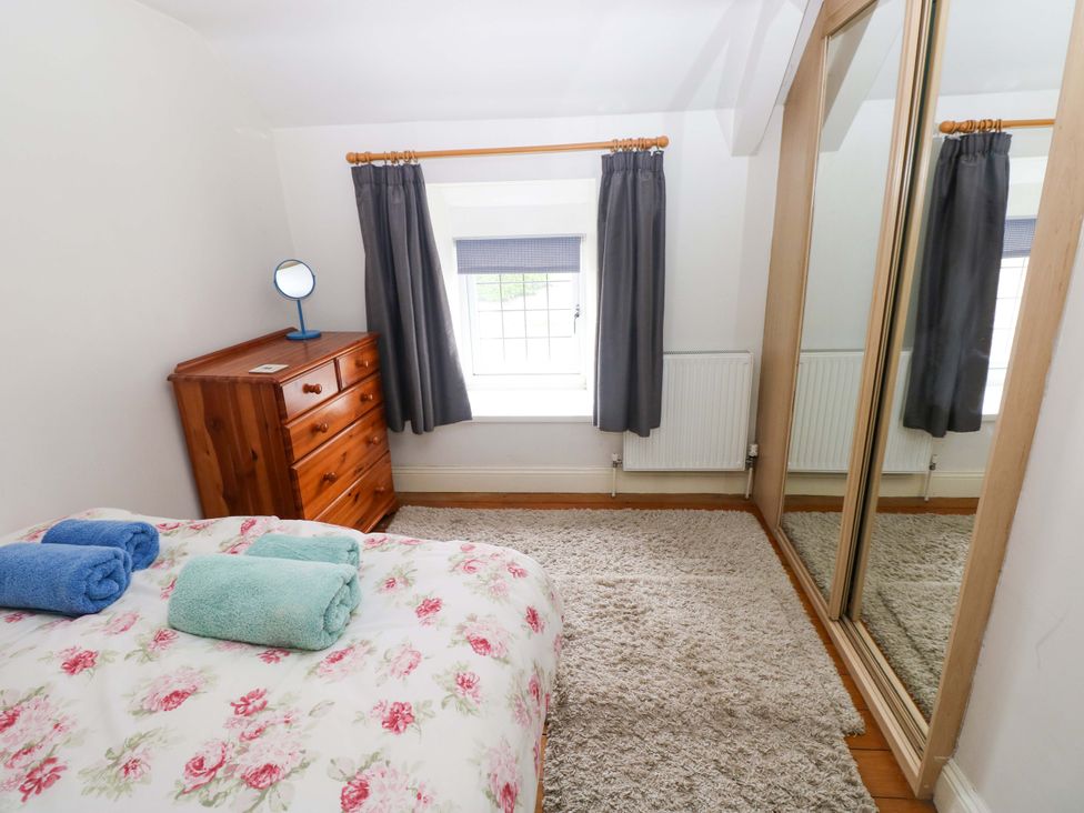 A bedroom with a bed and dresser at Milk Wood Cottage in Laugharne