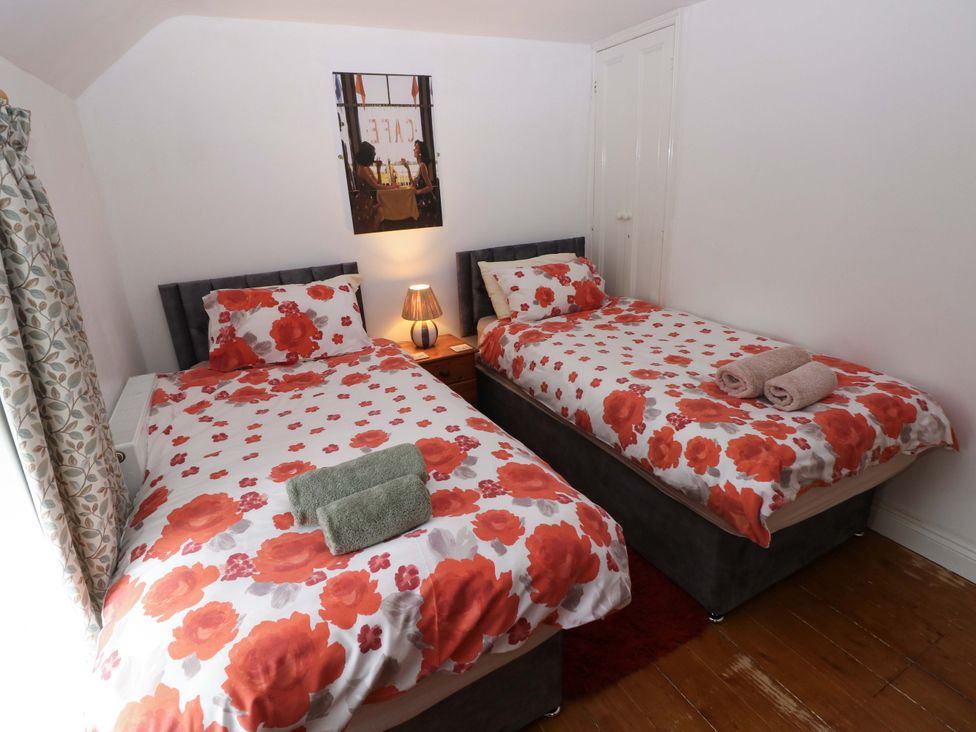 A bedroom with two beds and a bedside table at Milk Wood Cottage in Laugharne