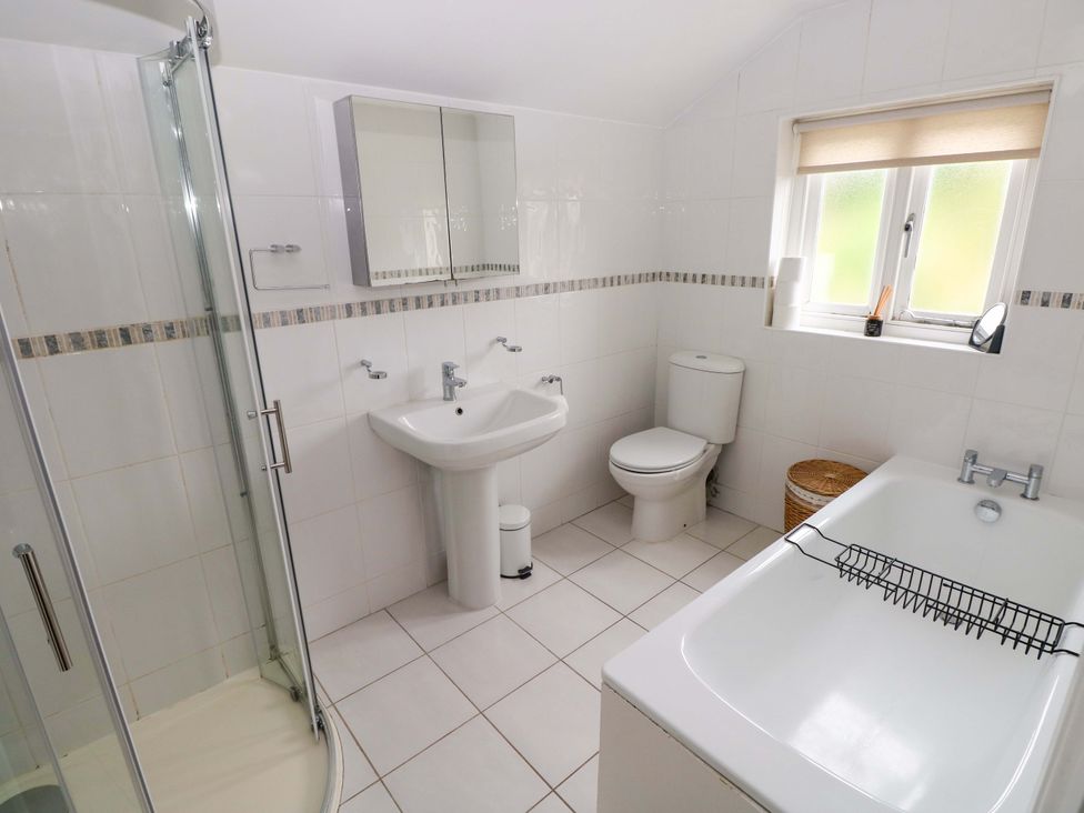 A bathroom with a shower, toilet, sink, and bath at Milk Wood Cottage in Laugharne