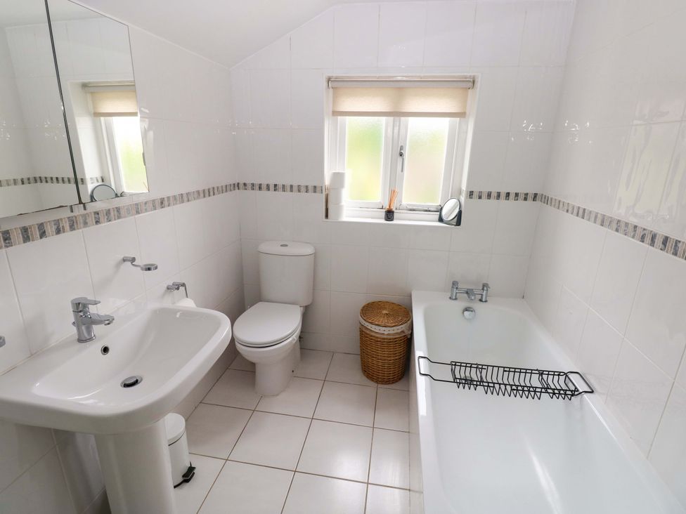 A bathroom with a sink, toilet, and bath tub at Milk Wood Cottage in Laugharne
