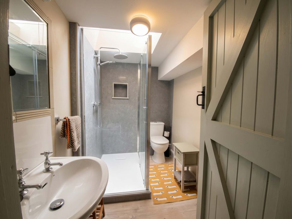 A bathroom featuring a sink, shower, toilet, and cabinet at The Coach House in Bitton