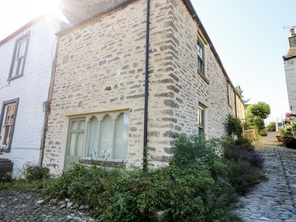 A house exterior with stone wall and plants at Castle Hill Cottage in Middleham, Wensleydale