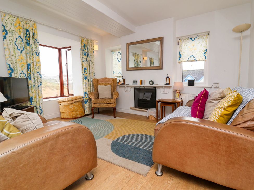 A living room with a sofa, armchair, and television at The Fort in Bude