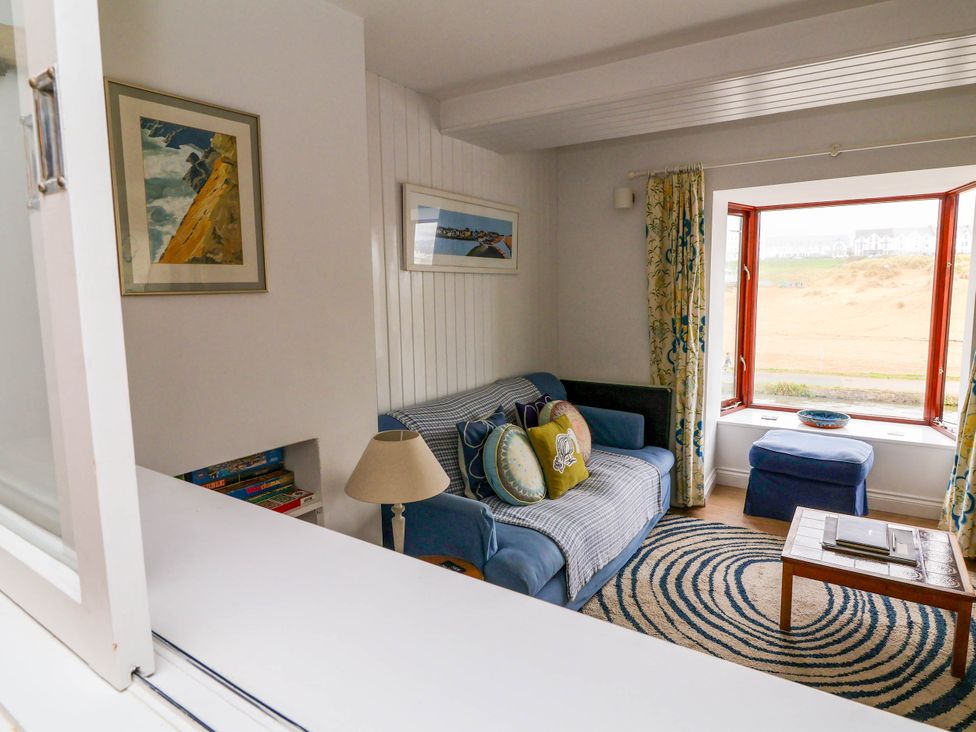A living room with a sofa, coffee table, and window at The Fort in Bude