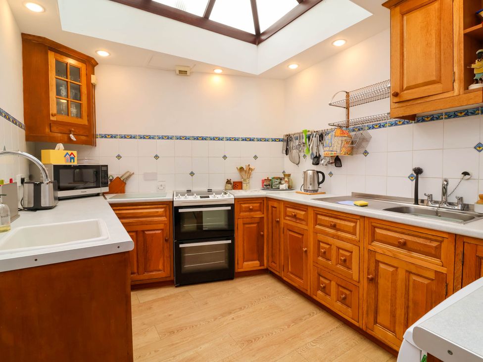 A kitchen with wooden cabinets and appliances at The Fort in Bude