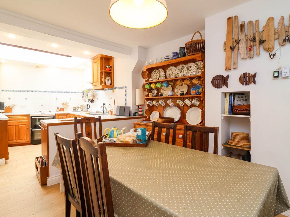 A kitchen with a wooden table and shelves of plates at The Fort in Bude