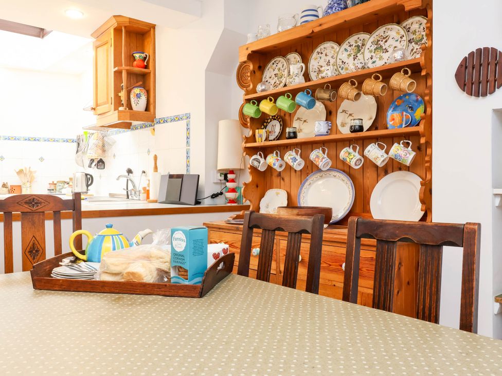 A kitchen with wooden table and shelf displaying kitchenware at The Fort in Bude