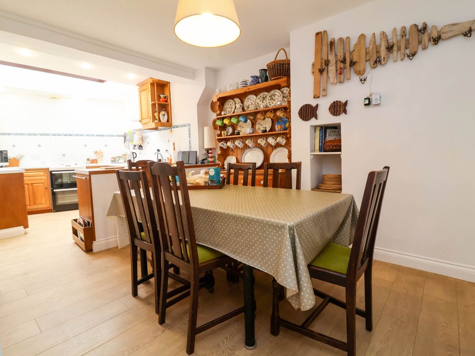 A dining room with a table and chairs and open kitchen at The Fort in Bude