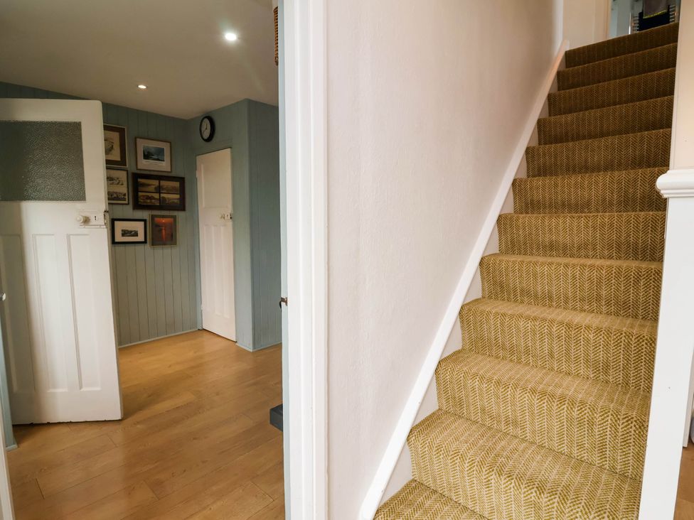 A hallway with a staircase and framed pictures at The Fort in Bude