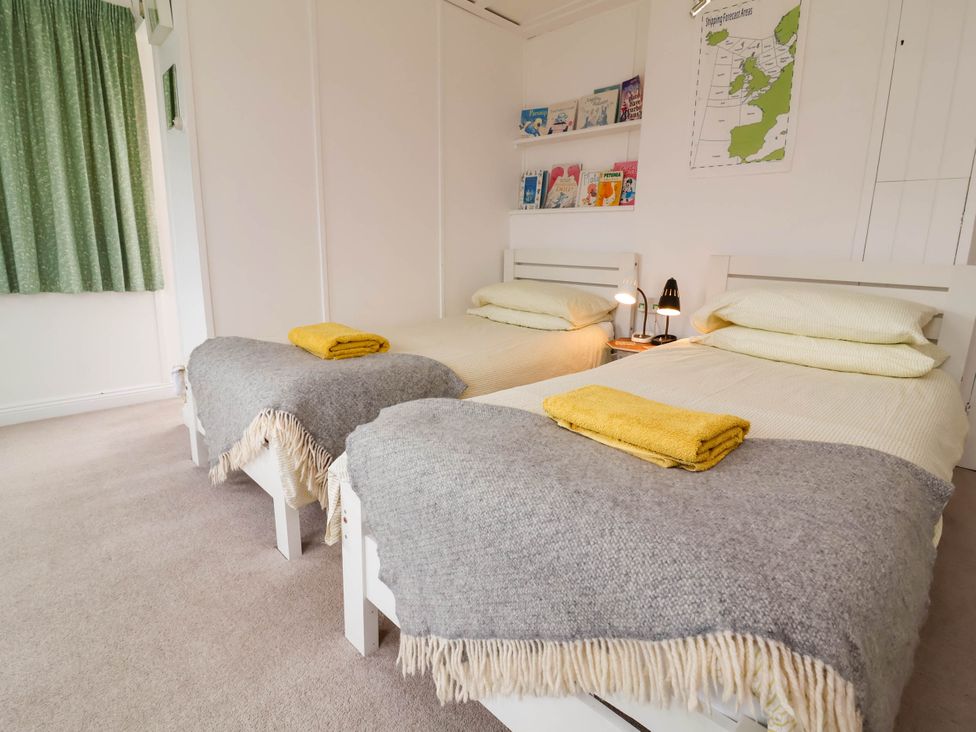 A bedroom with two beds and a shelf of books at The Fort in Bude