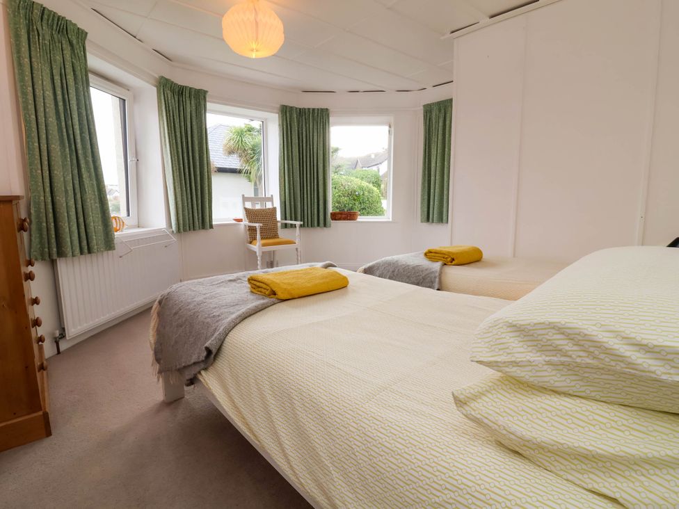 A bedroom with two beds and a chair by the window at The Fort in Bude