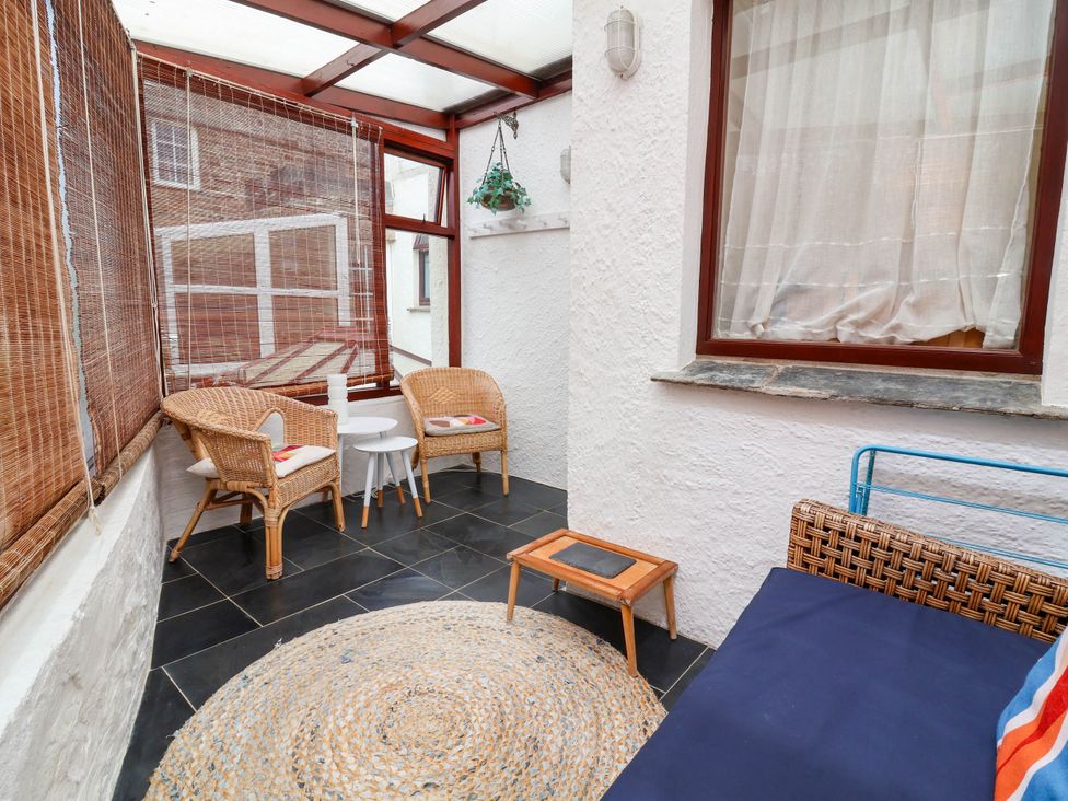 A conservatory with wicker chairs and a small table at The Fort in Bude