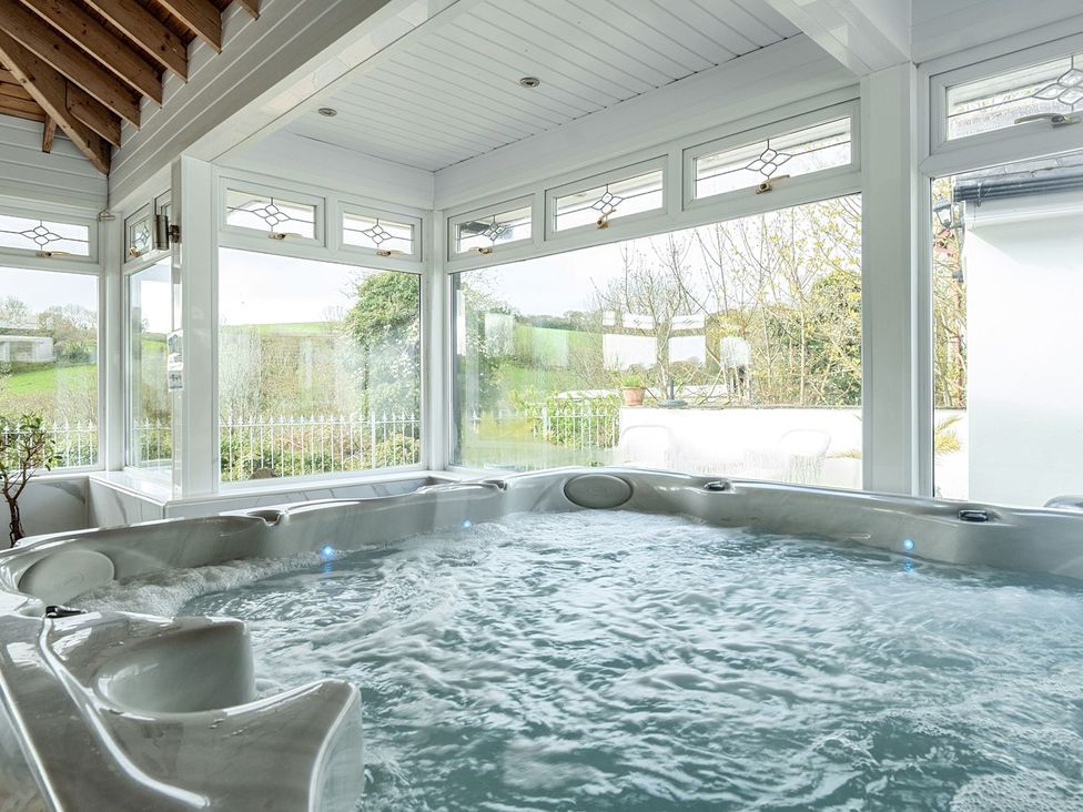 A hot tub surrounded by windows in an indoor pool area at Chapel Green Studio 2 Polgooth