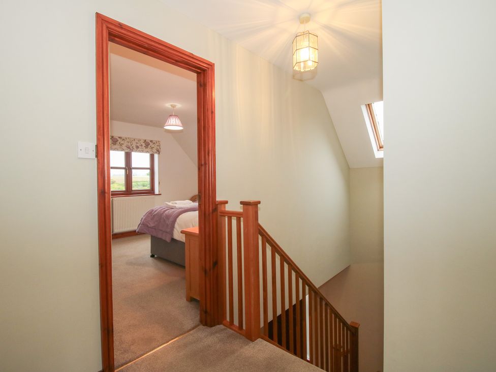 A hallway with a staircase and window at Byne Brook Cottage in Strefford near Craven Arms