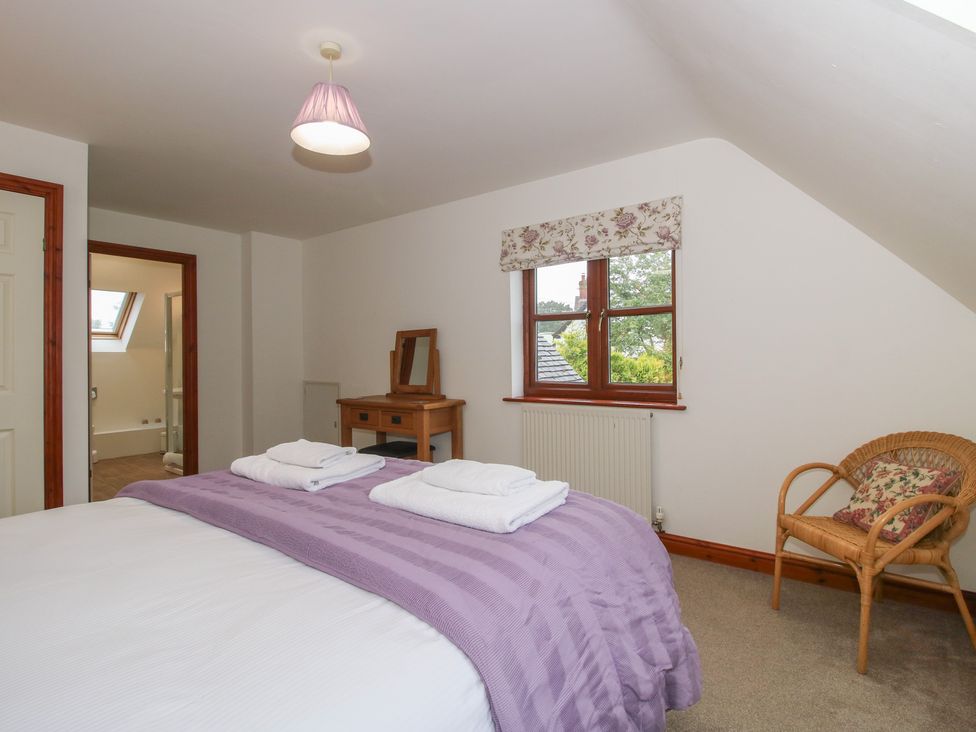 A bedroom with a bed and a chair at Byne Brook Cottage in Strefford near Craven Arms