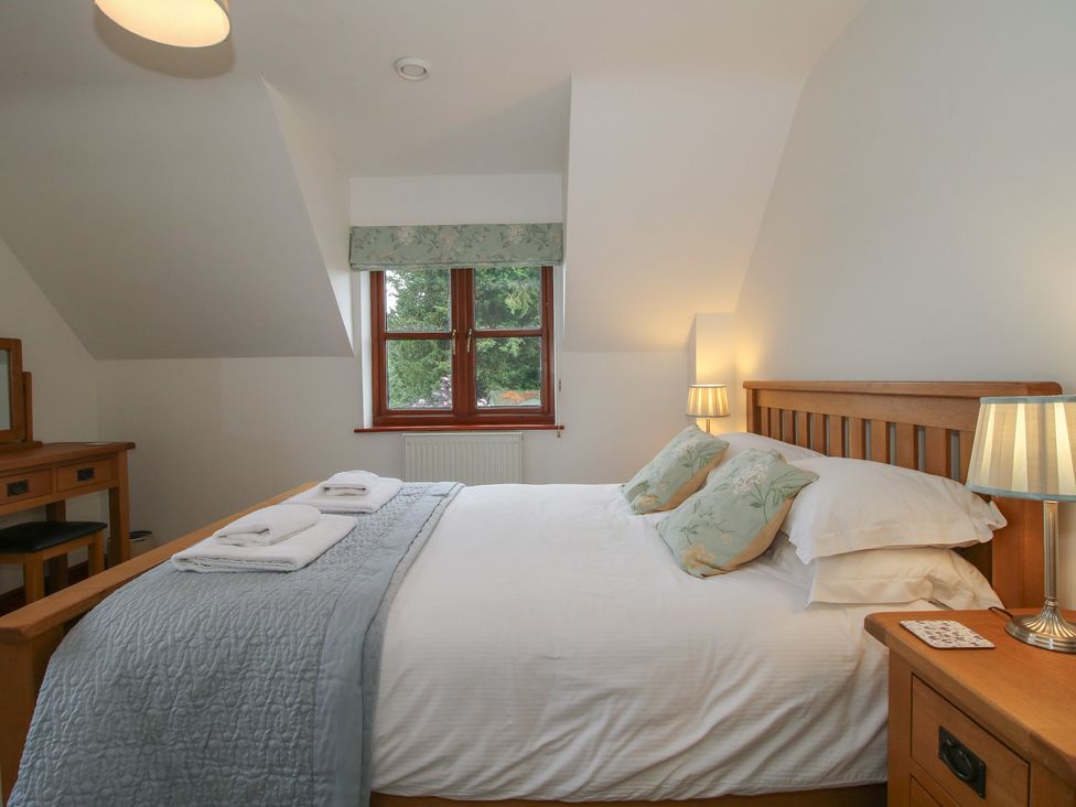 A bedroom with a bed and dressing table at Byne Brook Cottage in Strefford near Craven Arms