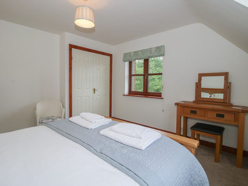 A bedroom with a bed, mirror, and window at Byne Brook Cottage Strefford near Craven Arms