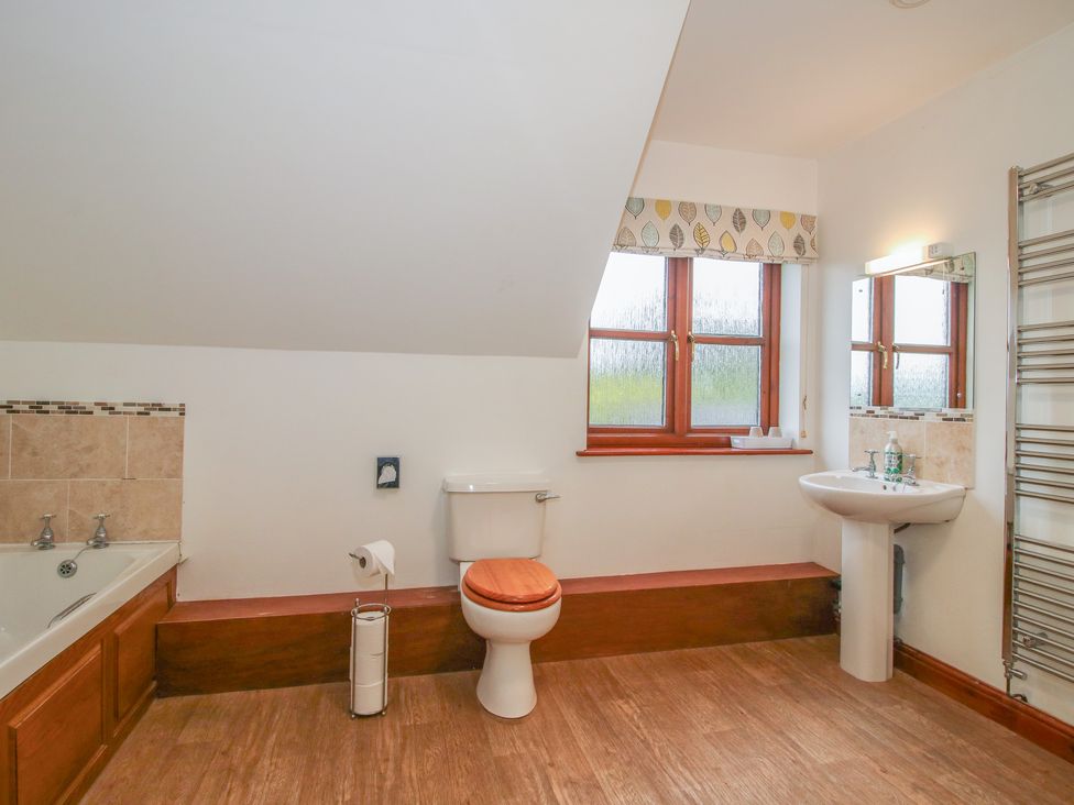 A bathroom with a bathtub, toilet, and sink at Byne Brook Cottage in Strefford near Craven Arms