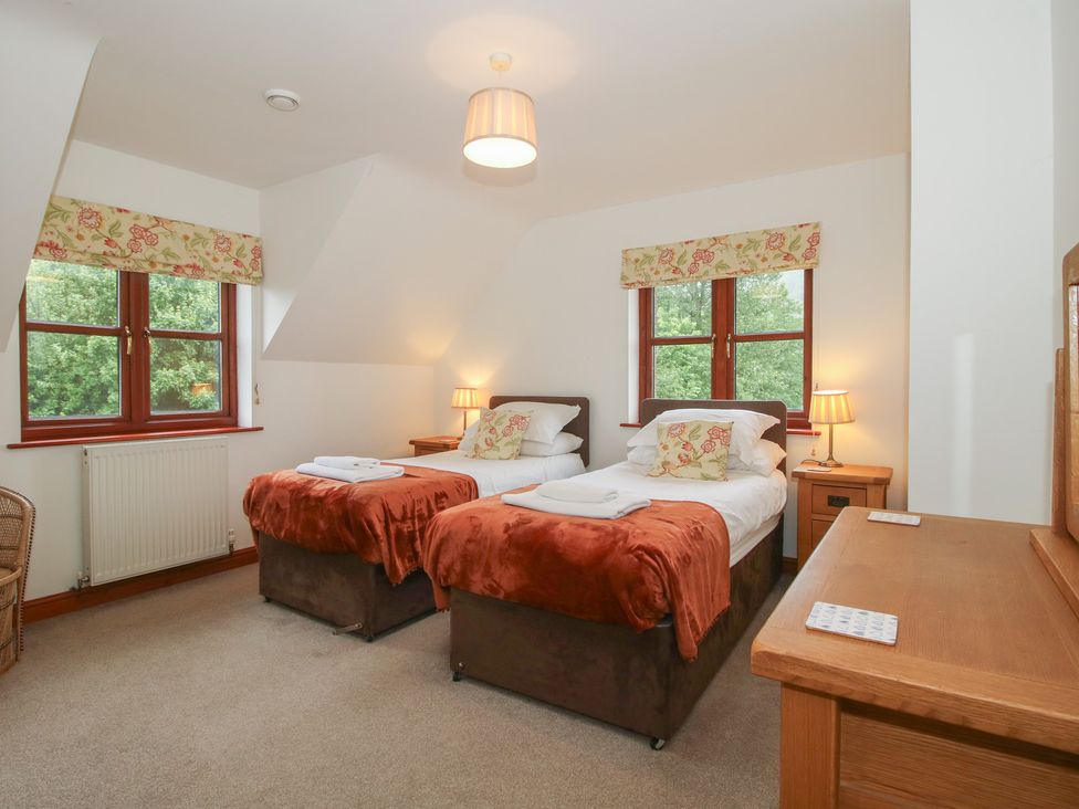 A bedroom with twin beds, a dresser, and windows at Byne Brook Cottage Strefford near Craven Arms