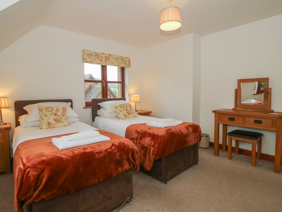 A bedroom with two beds and a desk at Byne Brook Cottage in Strefford near Craven Arms