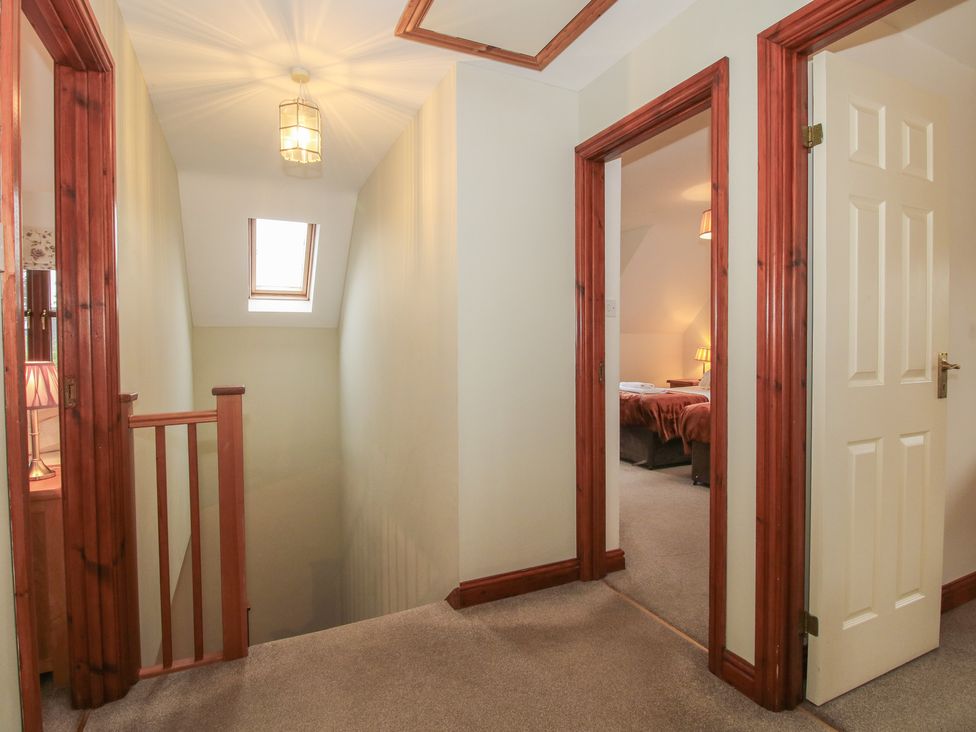 A hallway with a staircase and doors leading to other rooms at Byne Brook Cottage in Strefford near Craven Arms