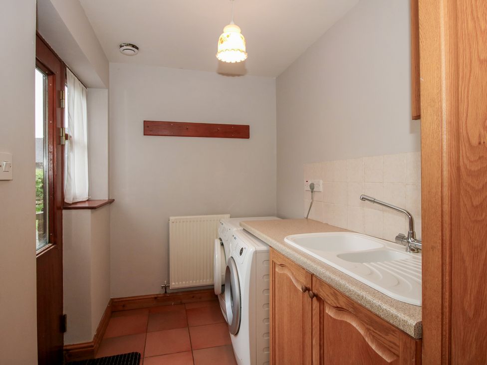 A laundry room with washing machine and sink at Byne Brook Cottage, Strefford near Craven Arms