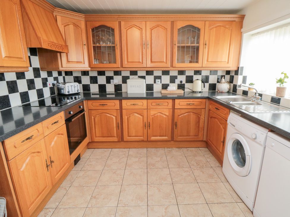 A kitchen with wood cabinets and appliances at Fairhaven Cottage, Ugthorpe near Runswick Bay