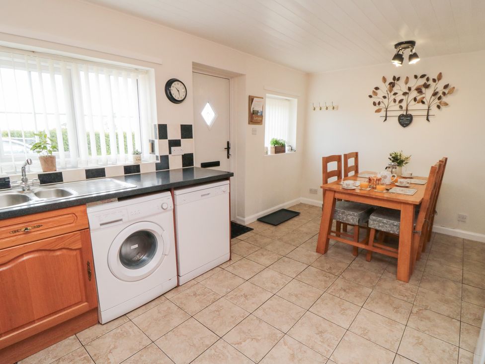A kitchen with a washing machine and table at Fairhaven Cottage in Ugthorpe near Runswick Bay
