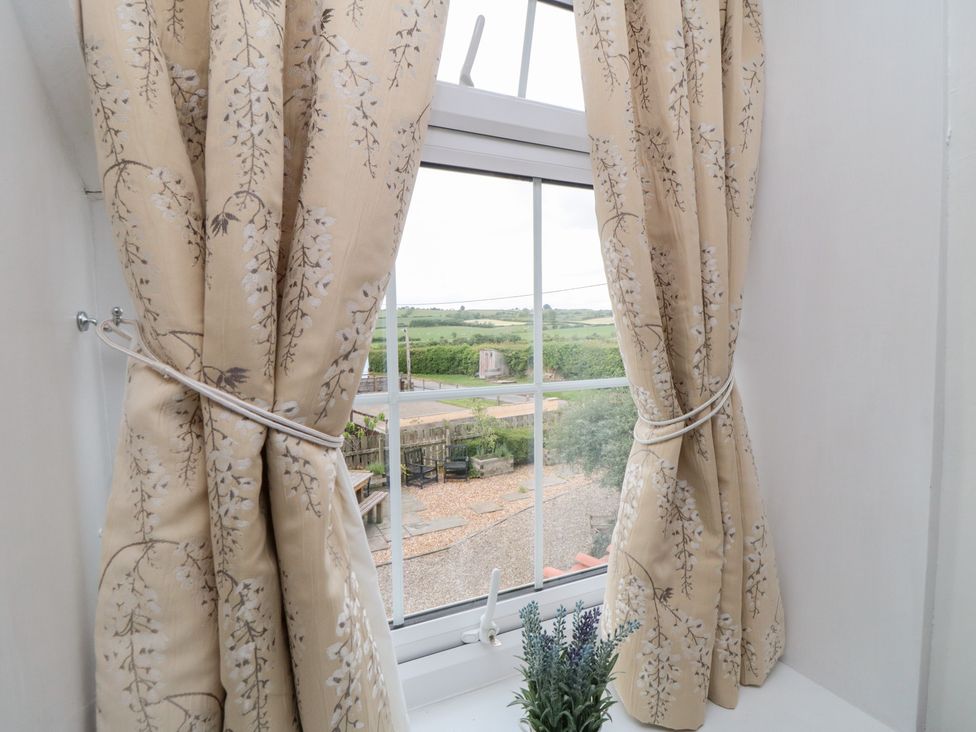 Curtains at a window with a view of a field at Fairhaven Cottage in Ugthorpe near Runswick Bay