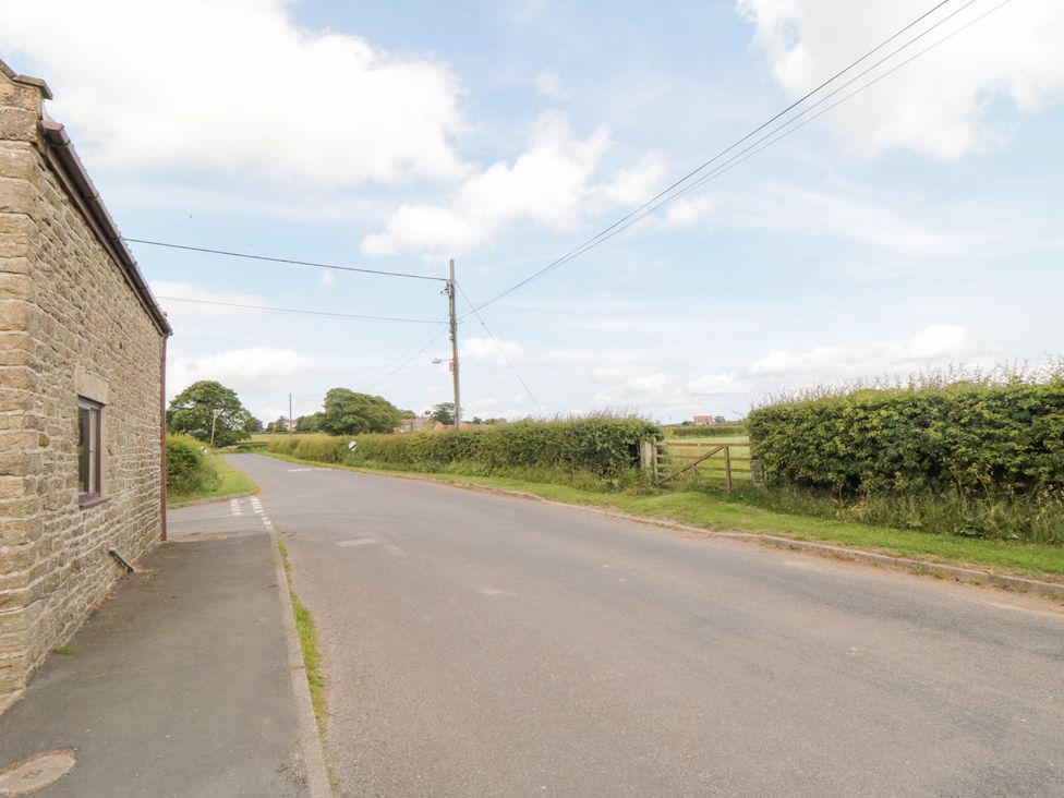 A view of a road with a stone building and hedges at Fairhaven Cottage Ugthorpe near Runswick Bay