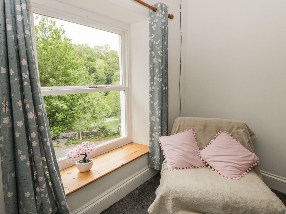 A sitting room with a window, curtains, and cushions at Teifi House in Cilgerran near Cardigan