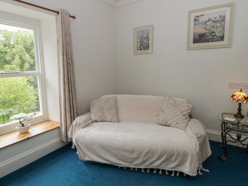 A living room with a sofa, lamp, and window at Teifi House in Cilgerran near Cardigan