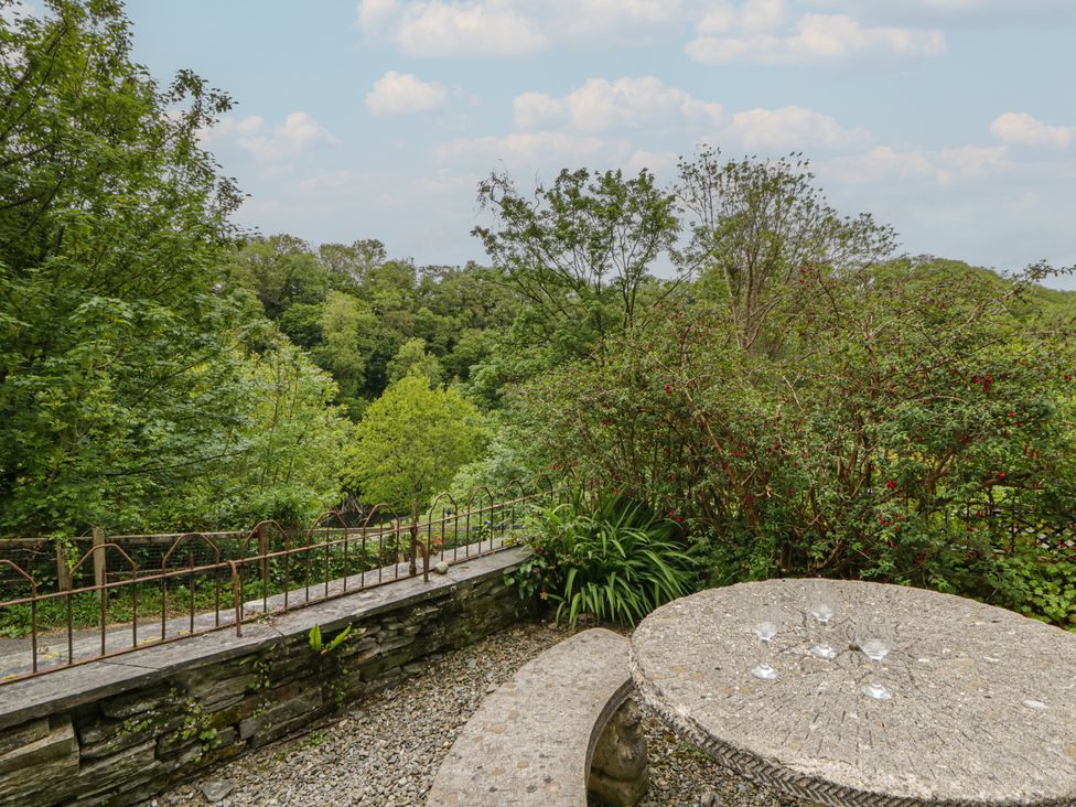 A garden setting with a stone table and glasses at Teifi House in Cilgerran near Cardigan
