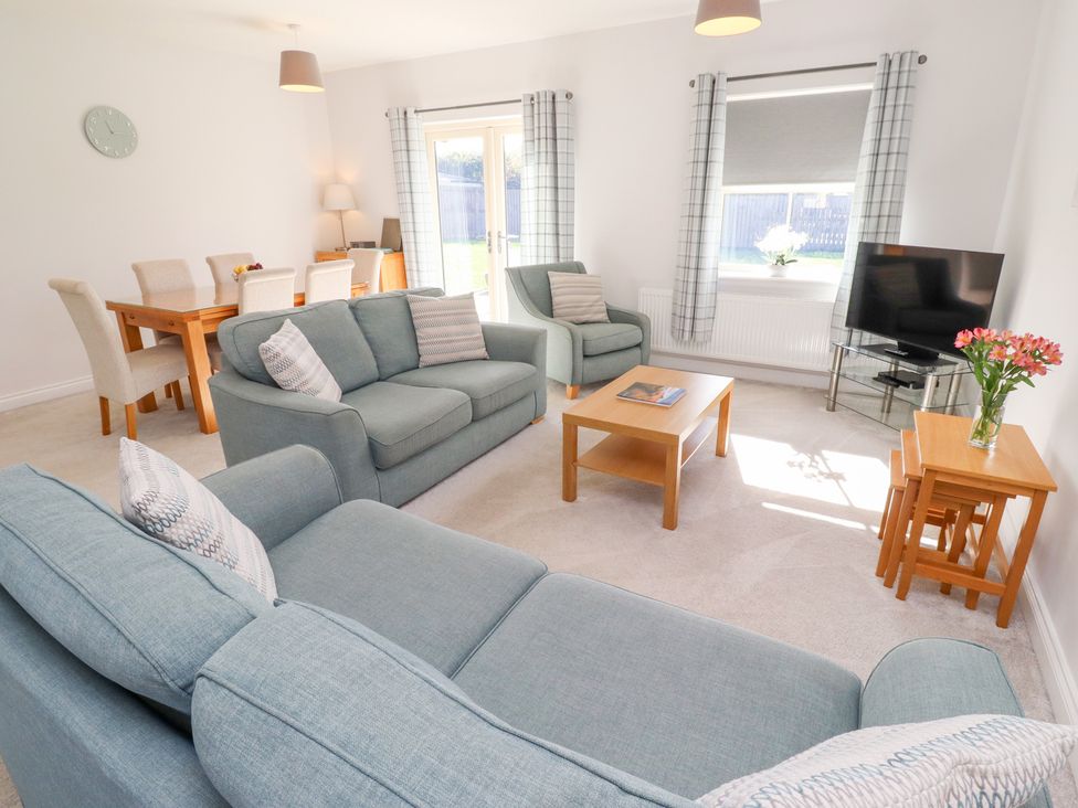 A living room with a sofa, dining table and television at The Haven in Embleton